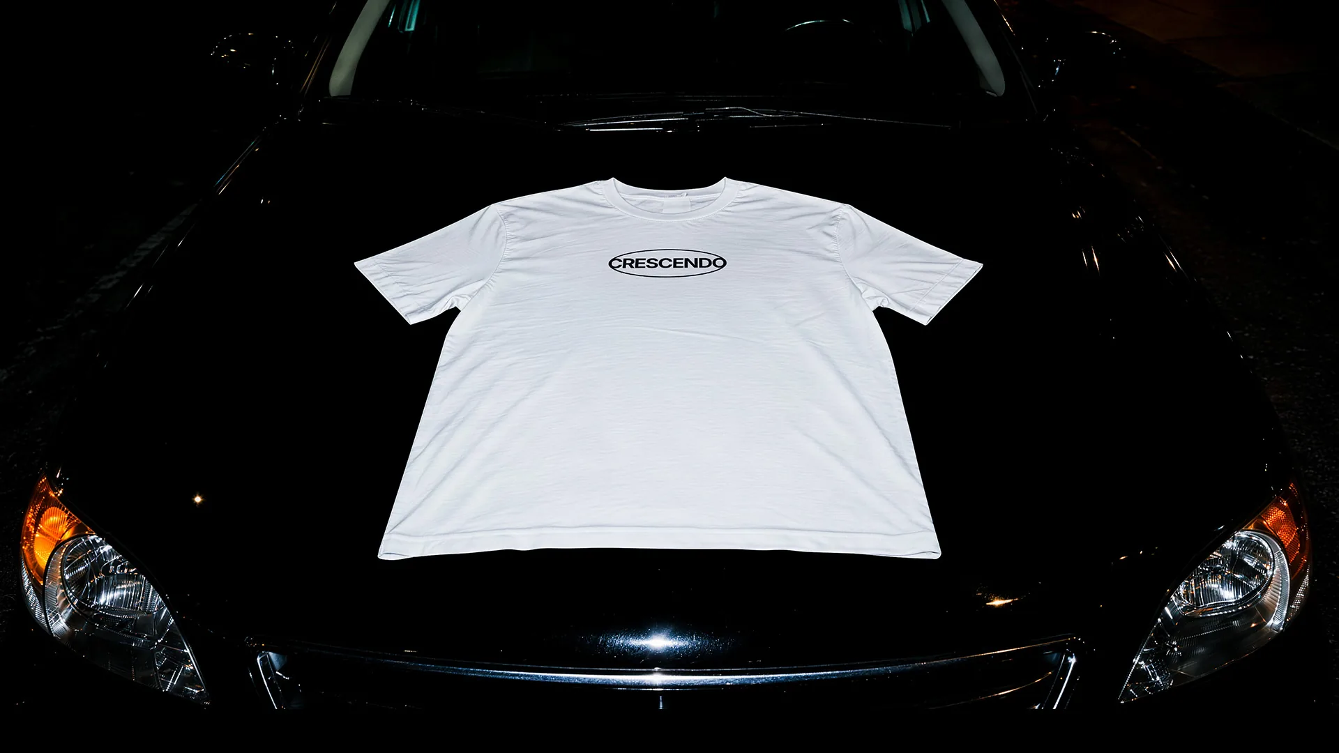Crescendo tee on a car bonnet at night