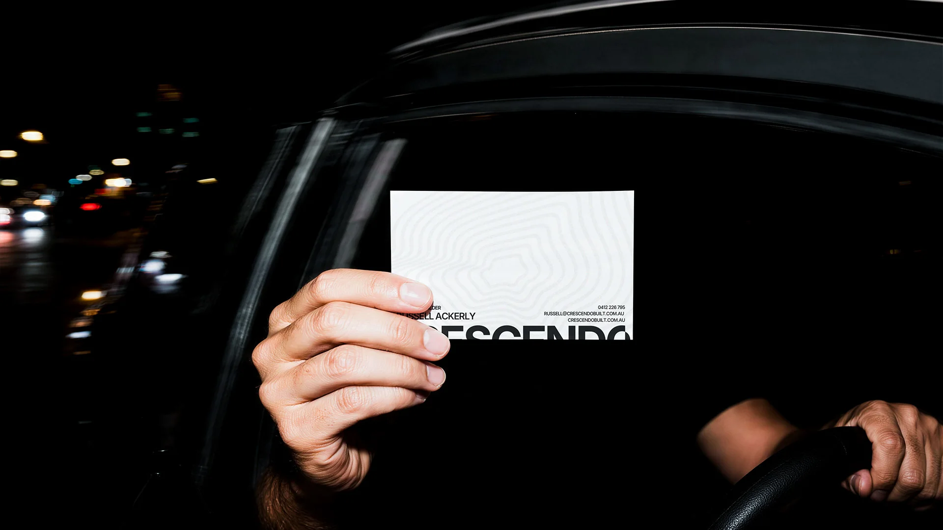 Business card held up in a car at night